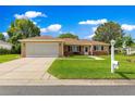 Charming single-story home with a well-manicured lawn and two-car garage, set against a backdrop of blue skies and fluffy clouds at 9790 Se 175Th St, Summerfield, FL 34491