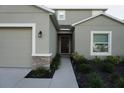 Home featuring an attached two-car garage, stone details, and simple landscaping at 1138 Calico Pointe Cir, Groveland, FL 34736