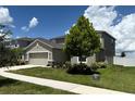 Two-story home with a large tree, neutral paint, two car garage, manicured landscaping, and a sidewalk at 1138 Calico Pointe Cir, Groveland, FL 34736