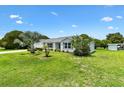 A bright home with a manicured front lawn with green grass and shrubs around the house at 1309 Lester Dr, The Villages, FL 32159