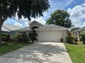 Attractive one-story home with a well-manicured lawn, mature trees, and a two-car garage at 15509 Markham Dr, Clermont, FL 34714