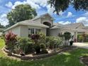 Landscaped front yard of a cozy home, featuring vibrant plants and a paved driveway at 15509 Markham Dr, Clermont, FL 34714
