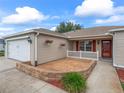 Inviting exterior with a brick-paved patio, white picket fence, and colorful flower baskets at 1948 Harston Trl, The Villages, FL 32162