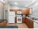 Functional kitchen features wood cabinets, white appliances, and ample counter space at 1948 Harston Trl, The Villages, FL 32162