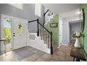 Inviting foyer with tile flooring, a staircase with black and white accents, and a decorative front door at 2108 Dogwood Cir, Mount Dora, FL 32757