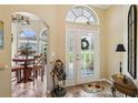 Welcoming foyer with decorative glass door, tile flooring, and arched doorway to the dining area at 2512 Baywater Rd, Tavares, FL 32778