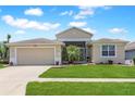 Single-story home with a well-manicured lawn, two-car garage, and neutral-toned exterior paint at 27328 Pine Straw Rd, Leesburg, FL 34748