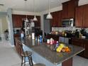 Features a spacious kitchen with dark wooden cabinets, granite countertops, and stainless steel appliances at 418 Winter Bliss Ln, Mount Dora, FL 32757