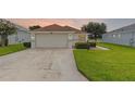 Inviting single-story home with a paved driveway, two-car garage, and beautifully maintained lawn at 5715 Illumination Ln, Leesburg, FL 34748