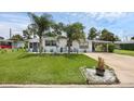 Well-maintained single-story home with a lush front lawn, palm trees, and a convenient carport at 1025 Capella Dr, Tavares, FL 32778