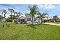 Single-story home with a large front yard, palm trees, and a well-manicured lawn at 1025 Capella Dr, Tavares, FL 32778