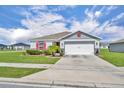 Charming single-story home featuring a two-car garage, well-maintained lawn, and colorful landscaping at 2488 Begonia St, Mascotte, FL 34753