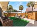 Secluded backyard patio with stylish furniture, artificial grass, tall wooden fence, and tropical palm trees at 2920 Poplar Ave, Leesburg, FL 34748