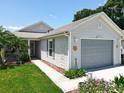 Well-maintained home with light gray siding, a palm tree, a two-car garage, and a manicured lawn at 4521 Eaglewood Dr, Leesburg, FL 34748