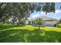 Expansive backyard featuring a lush lawn, mature trees, and outdoor seating area at 4904 Long Meadow Dr, Leesburg, FL 34748