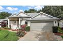 Well-maintained single-story home with a two-car garage, lush landscaping, and a bright exterior at 4904 Long Meadow Dr, Leesburg, FL 34748