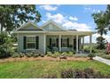 Charming single-story home with a covered porch and manicured lawn featuring meticulous landscaping at 622 W 11Th Ave, Mount Dora, FL 32757