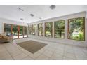 Sunroom filled with natural light through expansive windows, showcasing tile flooring and a comfortable chair at 7921 Sebago Ct, Orlando, FL 32835