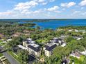 Aerial view of condo community surrounded by lush trees, a waterway and nearby neighborhoods under a blue sky at 101 N Grandview St # 103, Mount Dora, FL 32757