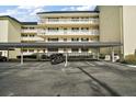 Photo showcases covered parking, with support posts and black motorcycle in front of white condo buildings at 101 N Grandview St # 103, Mount Dora, FL 32757