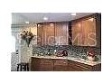 Galley-style kitchen featuring wood cabinets and mosaic backsplash at 1041 Reidville Rd, The Villages, FL 32162