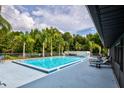 Community swimming pool with lounge chairs and nearby palm trees on a sunny day at 11926 Milan Way, Leesburg, FL 34788