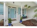 Inviting front porch with seating, potted plants, hanging flowers, and a stylish light blue front door at 15629 Catherine Cir, Groveland, FL 34736