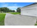 Attached garage with a smooth concrete driveway in front of a well-manicured lawn at 15629 Catherine Cir, Groveland, FL 34736