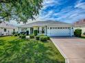 Charming single-story home featuring a well-manicured lawn and beautiful landscaping at 1675 Westminster Ct, The Villages, FL 32162