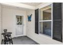 Inviting front porch featuring a decorative door, a blue butterfly decoration, and a small seating area at 17695 Se 84Th Peyton Ct, The Villages, FL 32162