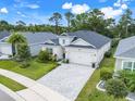 Well maintained single-story home features a two-car garage, manicured lawn and gray brick driveway at 1990 Wallingford Loop, Mount Dora, FL 32757