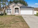 Attractive single-Gathering home featuring an arched entry, two-car garage, and manicured lawn at 2849 Doe Run Trl, Orange City, FL 32763