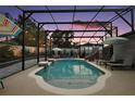 A screened pool with a slide and patio furniture sits in a lush backyard at 318 Stone Castle Loop, Lady Lake, FL 32159