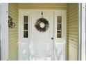Close-up of the white front door adorned with a decorative wreath and sidelights at 4300 Leafway Cir, Leesburg, FL 34748