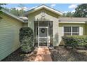 Charming front entrance featuring a screened enclosure and mature landscaping at 4300 Leafway Cir, Leesburg, FL 34748