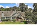 Aerial view of a quaint, well-maintained home with mature trees, green lawn, and charming front porch at 911 Beverly Harbors Dr # 16, Leesburg, FL 34748