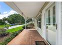 View of the front porch with brick flooring, a cozy swing, and manicured landscaping at 911 Beverly Harbors Dr # 16, Leesburg, FL 34748