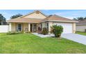 Inviting single-story home with a lush green lawn, colorful landscaping, and a convenient attached two-car garage at 10431 Reagans Run Dr, Clermont, FL 34711