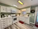 Well-maintained kitchen with white cabinetry, modern appliances, and durable laminate flooring at 117 Jacaranda Dr, Leesburg, FL 34748