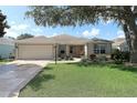 Inviting single-story home with lush green lawn, mature shade tree, and an attached two-car garage at 1412 Forest Acres Dr, The Villages, FL 32162