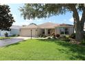 Charming single-story home with a well-manicured lawn, mature landscaping, and an attached two-car garage at 1412 Forest Acres Dr, The Villages, FL 32162