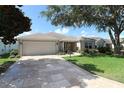 Attractive one-story home featuring a well-maintained lawn, elegant landscaping, and a spacious driveway leading to an attached garage at 1412 Forest Acres Dr, The Villages, FL 32162