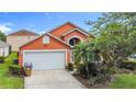 Charming orange two-story home with a two car garage and tropical landscaping at 167 Castaway Beach Way, Kissimmee, FL 34746