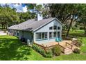 Back exterior of home featuring a deck, lush lawn, mature landscaping, and large windows at 168 Pond Rd, Mount Dora, FL 32757