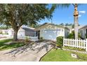 Home featuring a white picket fence, attached garage, and well-maintained landscaping at 16938 Se 94Th Sunnybrook Cir, The Villages, FL 32162