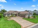 Well-maintained single-story home featuring a paver driveway, neutral paint, shutters and manicured landscaping at 17599 Se 121St Cir, Summerfield, FL 34491