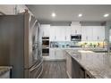 Modern kitchen features white cabinets, stainless steel appliances, a stylish backsplash, and granite countertops at 2136 Lula Rd, Minneola, FL 34715