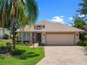 Charming single Gathering home boasting a lush lawn, mature trees, and a paved driveway on a sunny day at 4814 Saint Andrews Arc, Leesburg, FL 34748