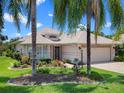Charming single Gathering home boasting a lush lawn, mature trees, and a paved driveway on a sunny day at 4814 Saint Andrews Arc, Leesburg, FL 34748