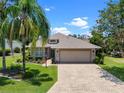 Charming single Gathering home boasting a lush lawn, mature trees, and a paved driveway on a sunny day at 4814 Saint Andrews Arc, Leesburg, FL 34748